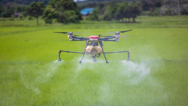 a drone with spray coming out of it flying over a field